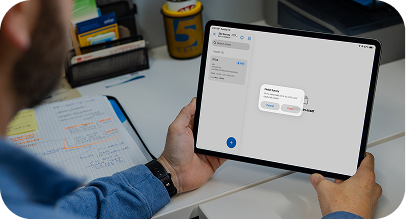 Man in blue shirt holding tablet with a digital note-taking app open on screen.