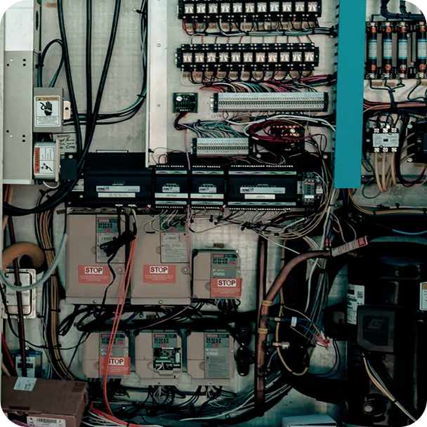 Electrical control panel with circuit breakers, relays, wiring, labeled STOP modules, and connectors.