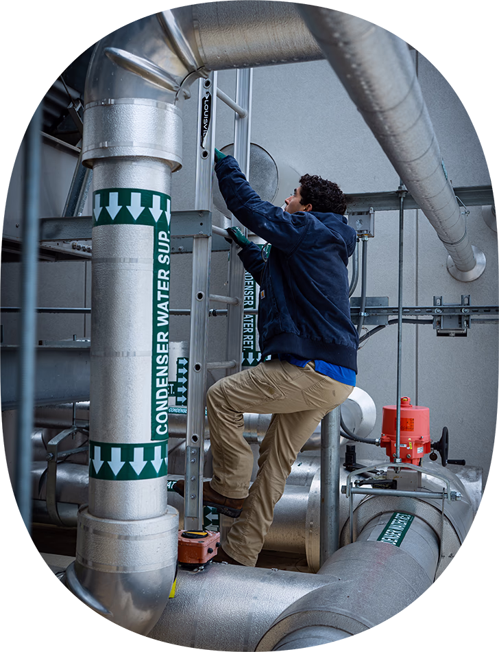 Worker in blue jacket climbing a metal ladder.