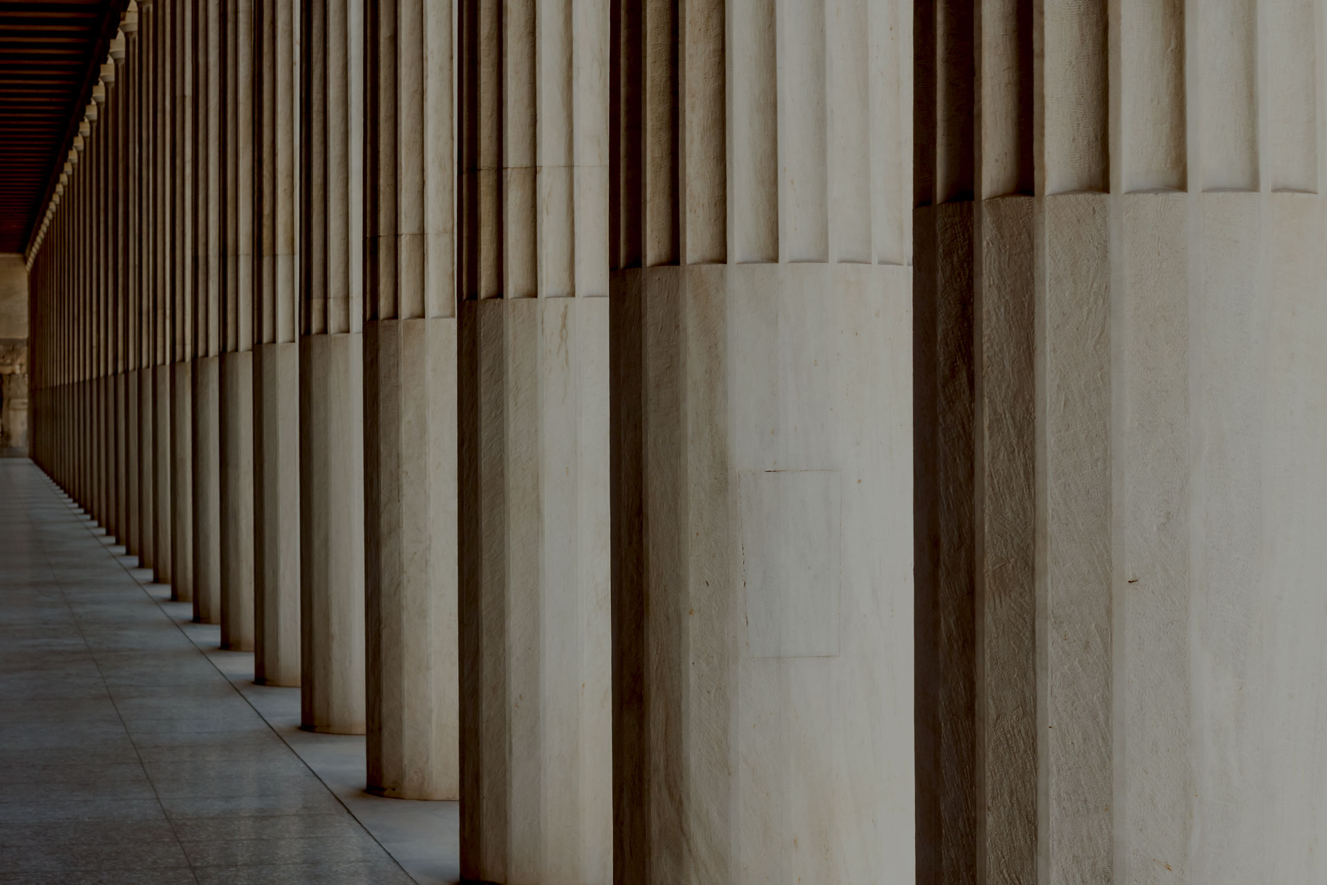 Long row of tall, fluted stone columns creating a classical architectural corridor.