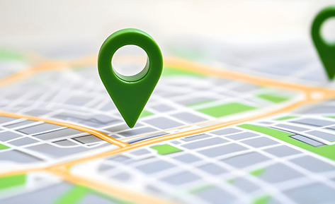 Close-up of a green location pin marking a spot on a digital map with streets and blocks.