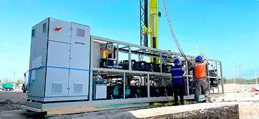 Dos técnicos ensamblando equipo industrial grande en estructura metálica al aire libre.