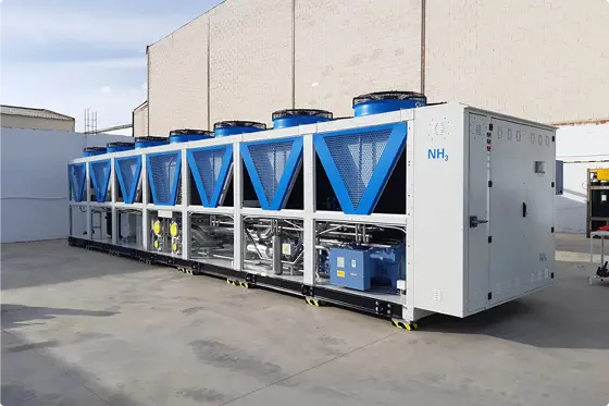Unidad grande de enfriamiento industrial con ventiladores azules instalados afuera de una fábrica.
