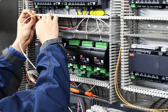 Persona trabajando con cables eléctricos dentro de un panel de control de automatización industrial.