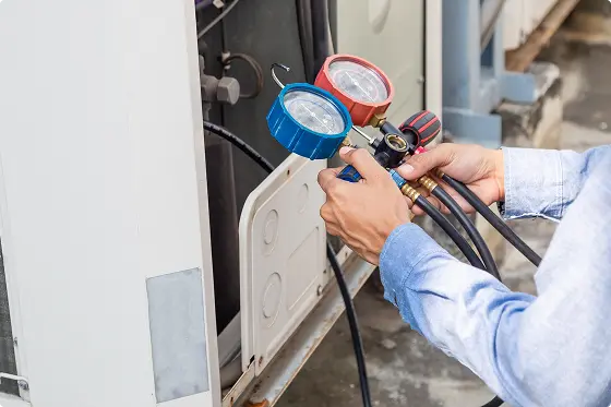 Manos con manómetros ajustando el sistema HVAC de una unidad exterior en un techo.