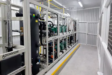Sistema de refrigeración industrial con múltiples compresores y tuberías en una sala técnica.