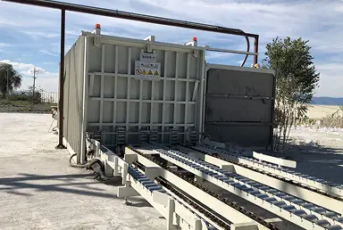 Enfriador al vacío industrial al aire libre con rieles metálicos y cielo despejado.