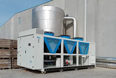 Unidad de aire acondicionado industrial con ventiladores azules junto a un edificio gris.