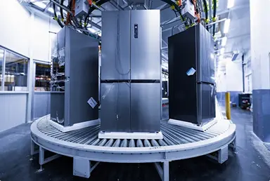 Tres refrigeradores de acero inoxidable en una cinta transportadora dentro de una fábrica moderna.