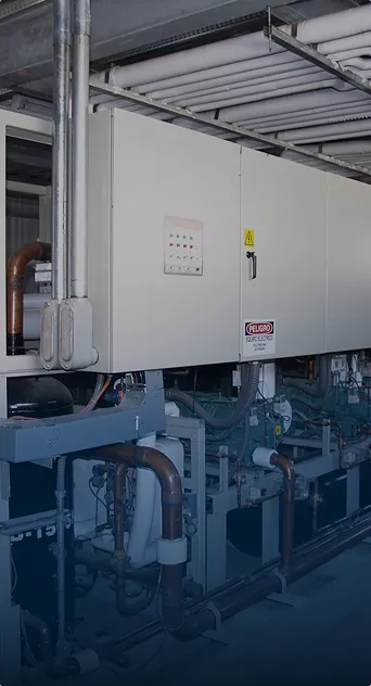 Máquina industrial con tuberías y panel de control con aviso de peligro en área industrial.
