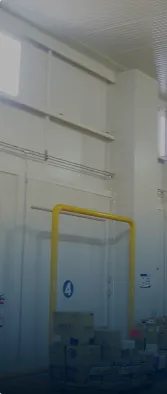 Interior de bodega con paredes blancas, puerta con señal número 4 y cajas apiladas.