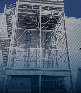 Estructura metálica industrial alta con escaleras al lado y paneles debajo bajo cielo azul.