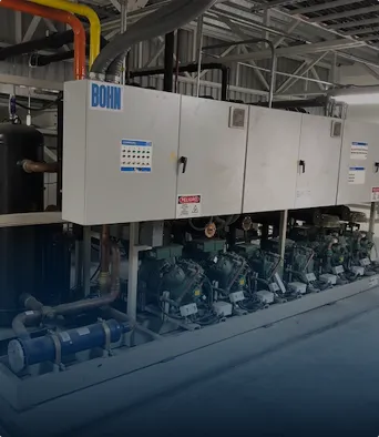 Unidad de compresores industriales conectados a paneles eléctricos en un ambiente industrial.