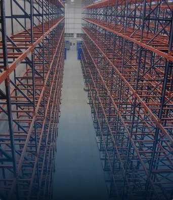 Pasillo vacío entre estructuras metálicas de estanterías en un almacén grande y bien iluminado.