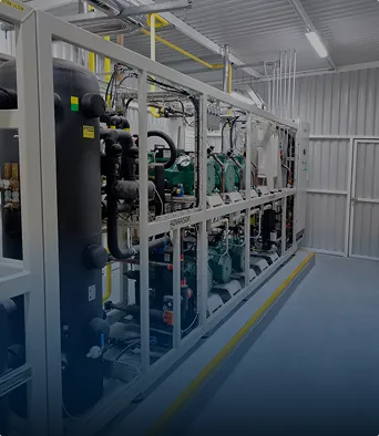 Interior de planta procesadora con maquinaria industrial y sistemas de tuberías en un área limpia.