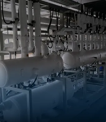 Tuberías industriales y tanques blancos conectados en un sistema dentro de una planta o fábrica.