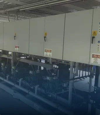Paneles eléctricos industriales montados sobre estructuras con tuberías y advertencias de peligro.