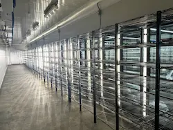 Pasillo largo con estanterías metálicas vacías en un cuarto frío industrial bien iluminado.