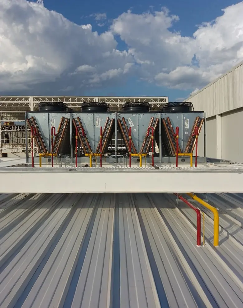 Cuatro unidades grandes de aire acondicionado instaladas en el techo de un edificio industrial.