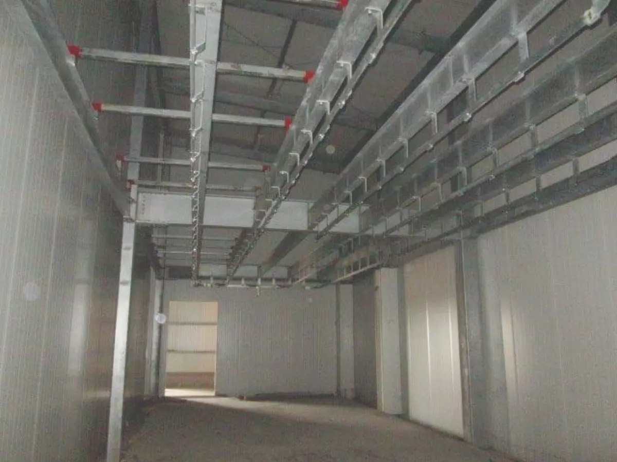 Interior de una habitación industrial vacía con vigas metálicas y paredes blancas.