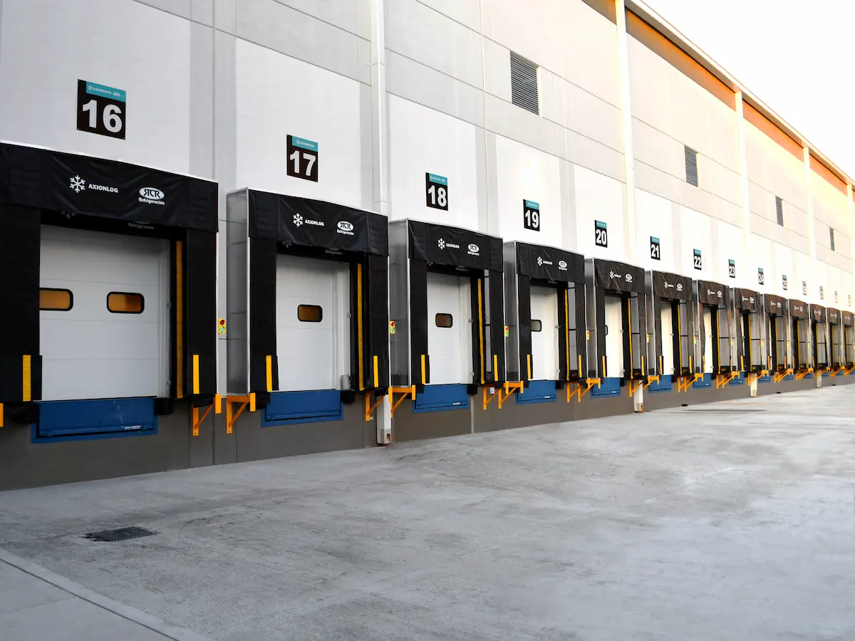 Área de carga con varias puertas de muelle numeradas del 16 al 26 en un edificio industrial.