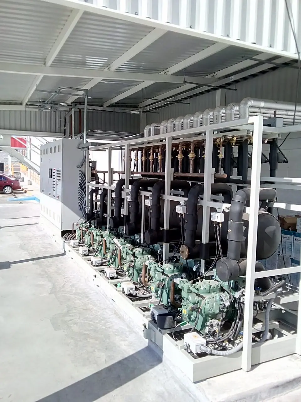 Múltiples compresores industriales alineados en una estructura metálica en un área techada.