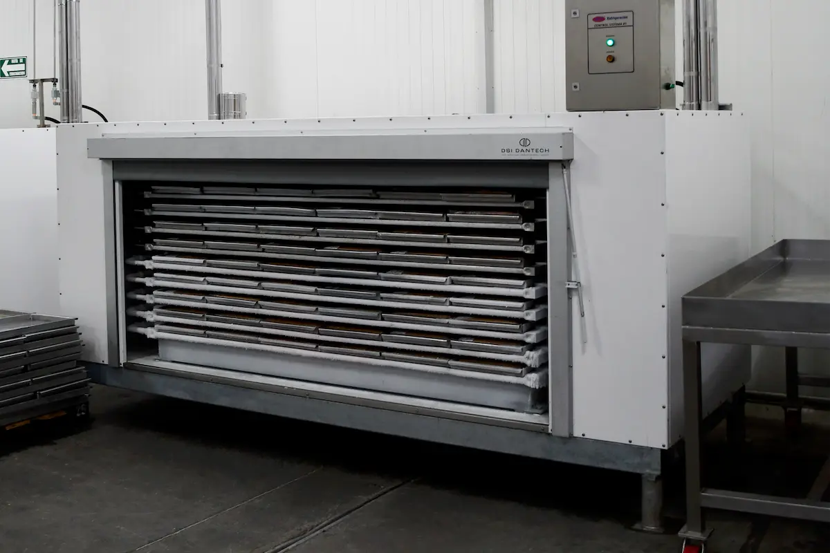 Máquina industrial de secado con bandejas horizontales en un ambiente de fábrica limpio.