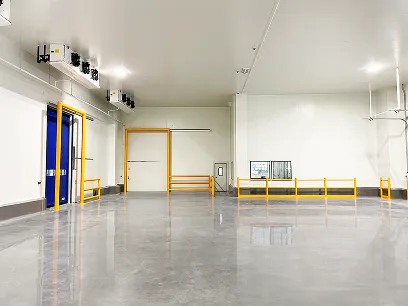 Interior de un almacén industrial limpio con puertas azules y amarillas y piso pulido brillante.