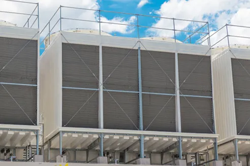 Grandes chillers industriales exteriores debajo de un cielo azul con nubes blancas.