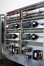 Cuadro eléctrico con varios componentes y cables organizados en rieles industriales.