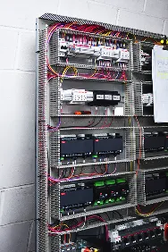 Panel eléctrico con múltiples cables, interruptores y componentes organizados en un gabinete metálico.