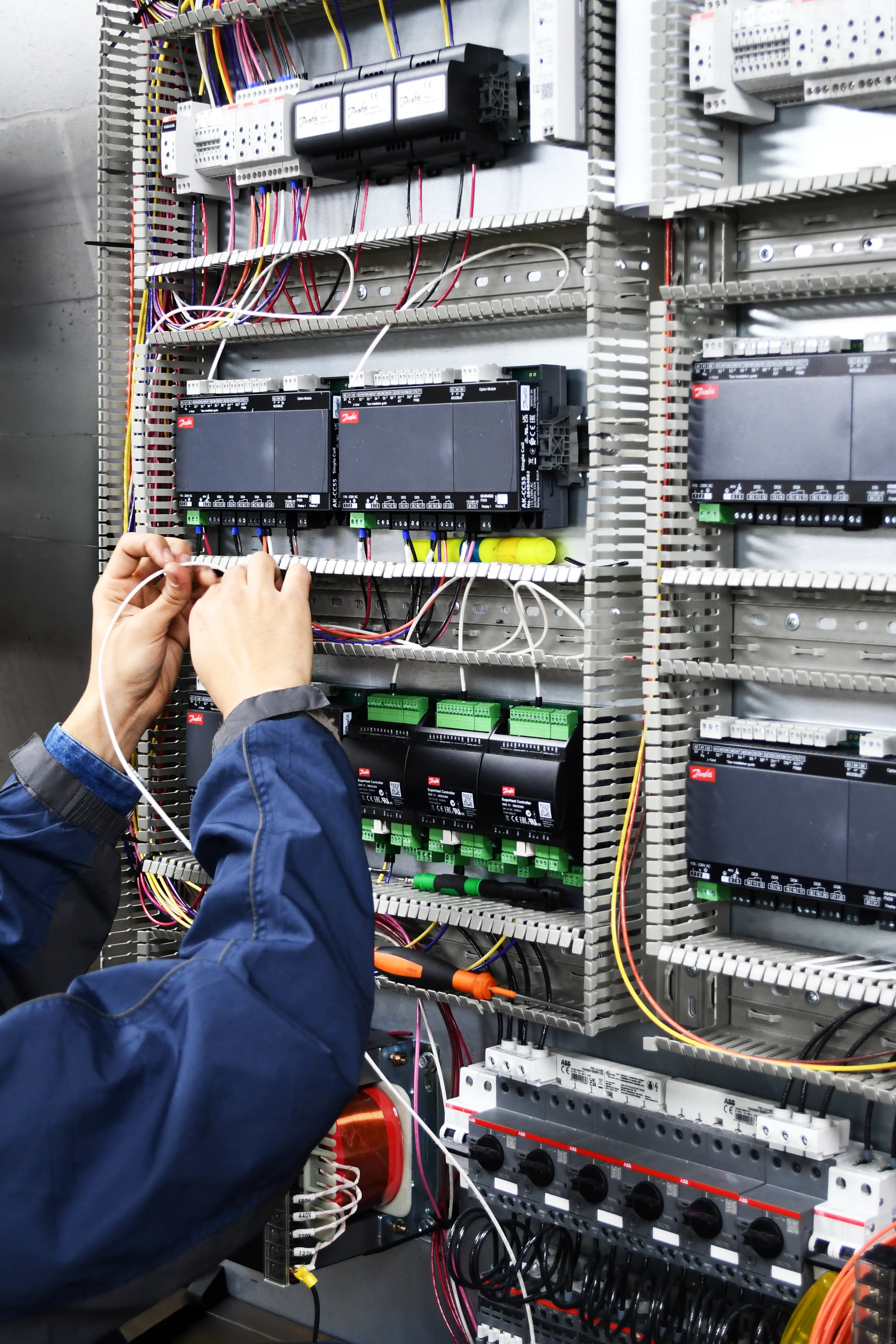 Manos de un técnico trabajando en el cableado de un panel eléctrico complejo.