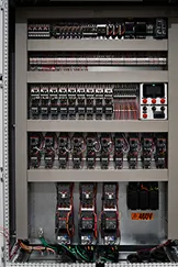 Panel eléctrico con interruptores automáticos, relés y componentes de circuito organizados en filas.