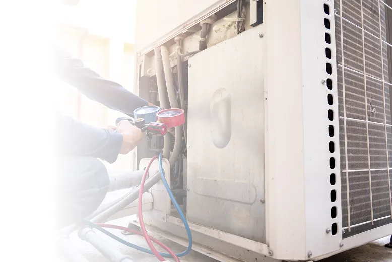 Persona revisando un medidor en un equipo de aire acondicionado exterior para mantenimiento.