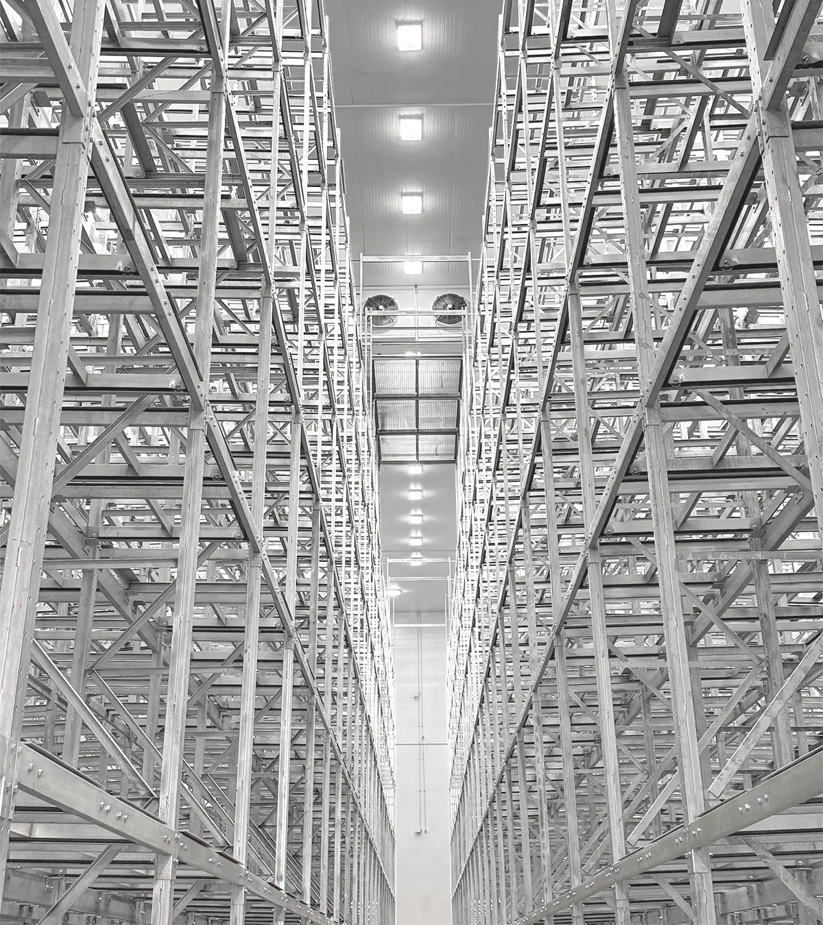 Estanterías metálicas altas y vacías alineadas en un almacén industrial bien iluminado.