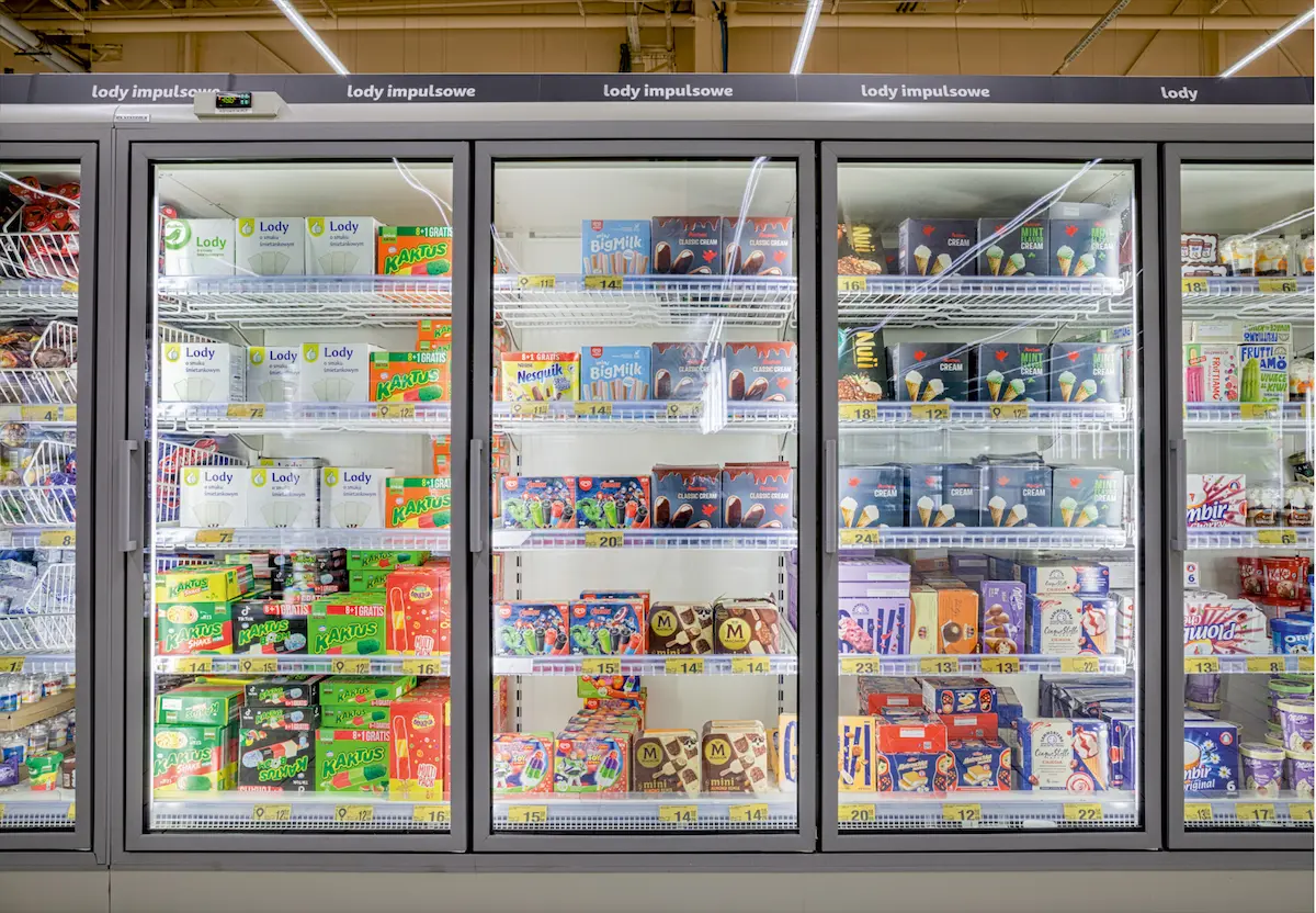Congelador de supermercado con varios helados empaquetados en estantes iluminados.
