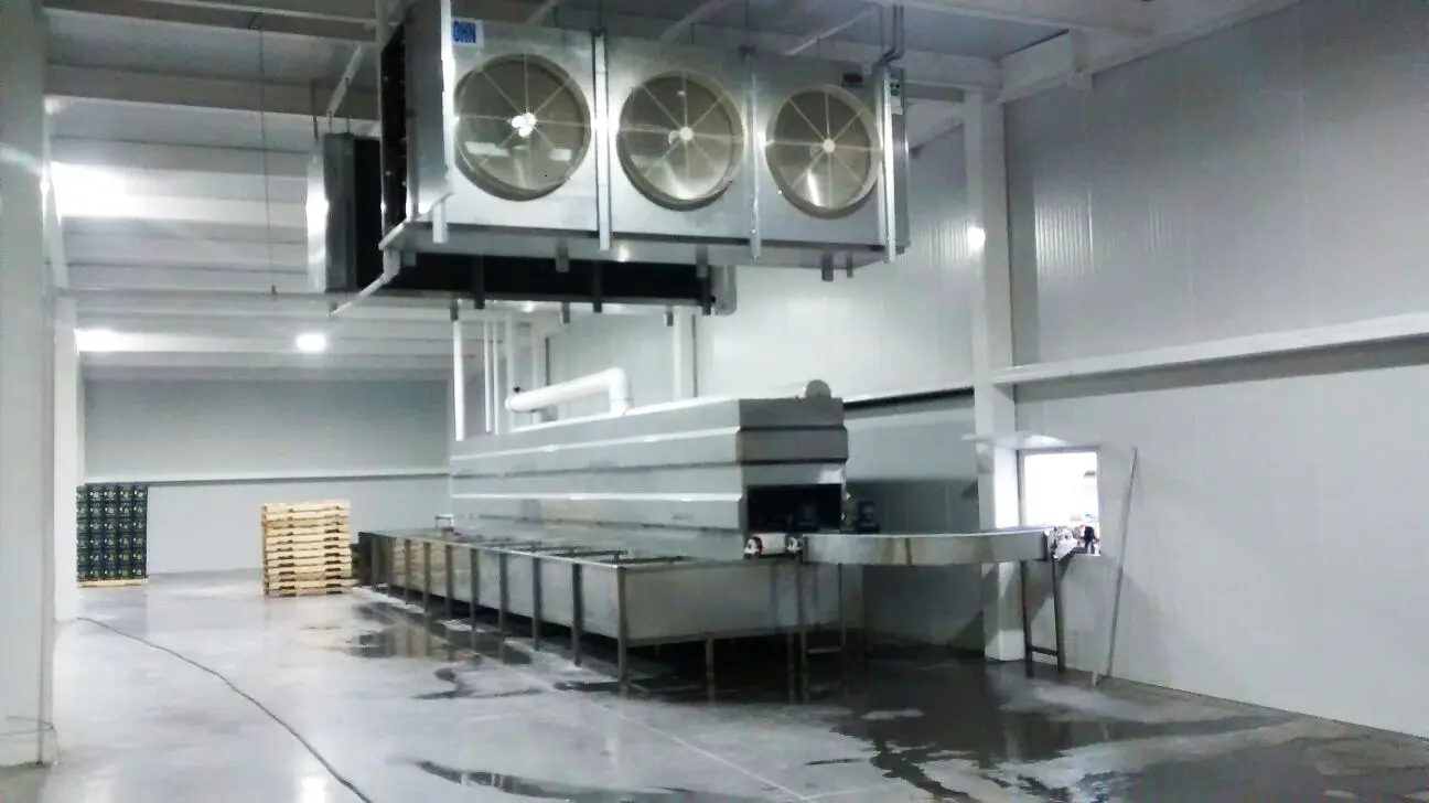 Máquina industrial de enfriamiento en nave con ventiladores grandes y plataforma metálica.