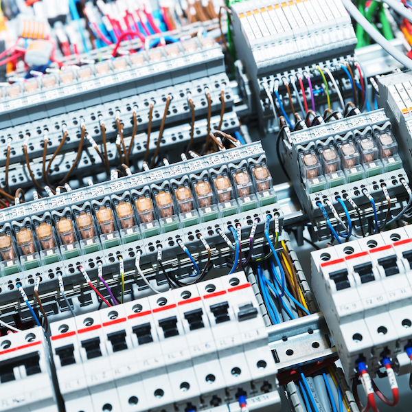Panel eléctrico con múltiples disyuntores, relés y cables conectados de varios colores.