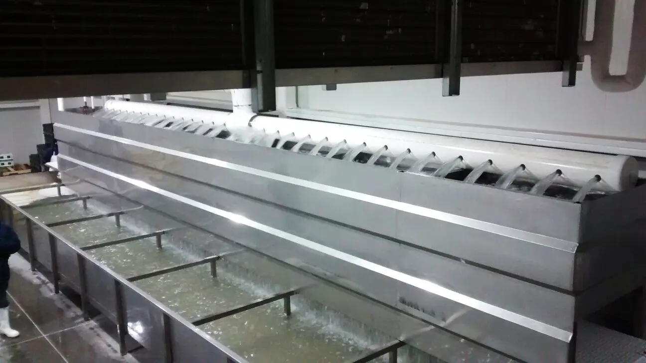 Máquina industrial en acero inoxidable con flujo constante de agua en bandejas y tuberías.