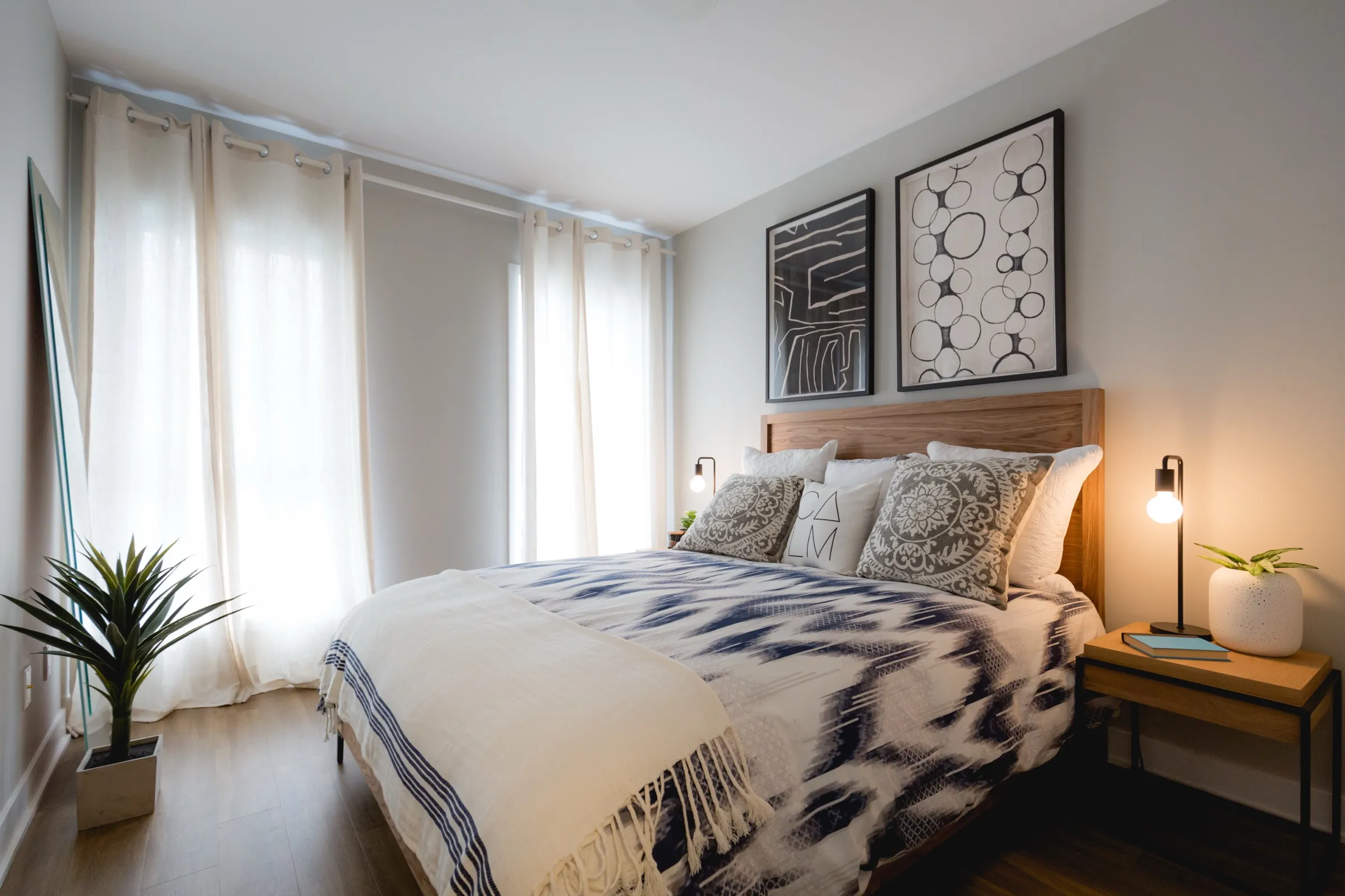 Chambre d’une unité de Mostra Longueuil, lit habillé et grande fenêtre