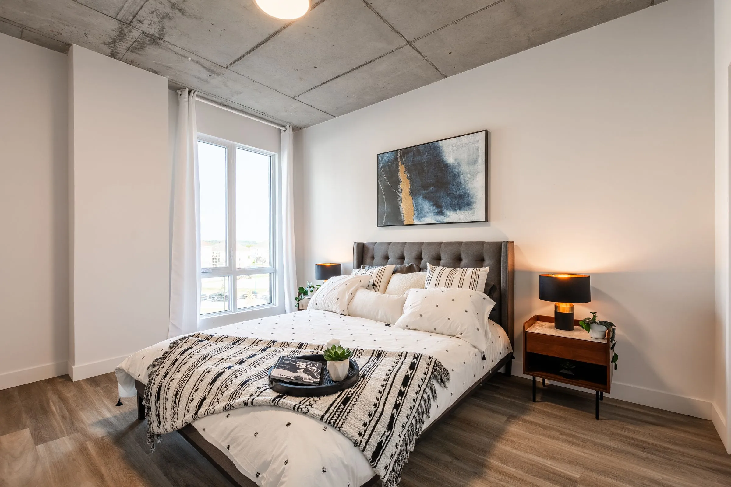 Chambre d’une unité de Mostra Mascouche avec fenêtre et plafond de béton