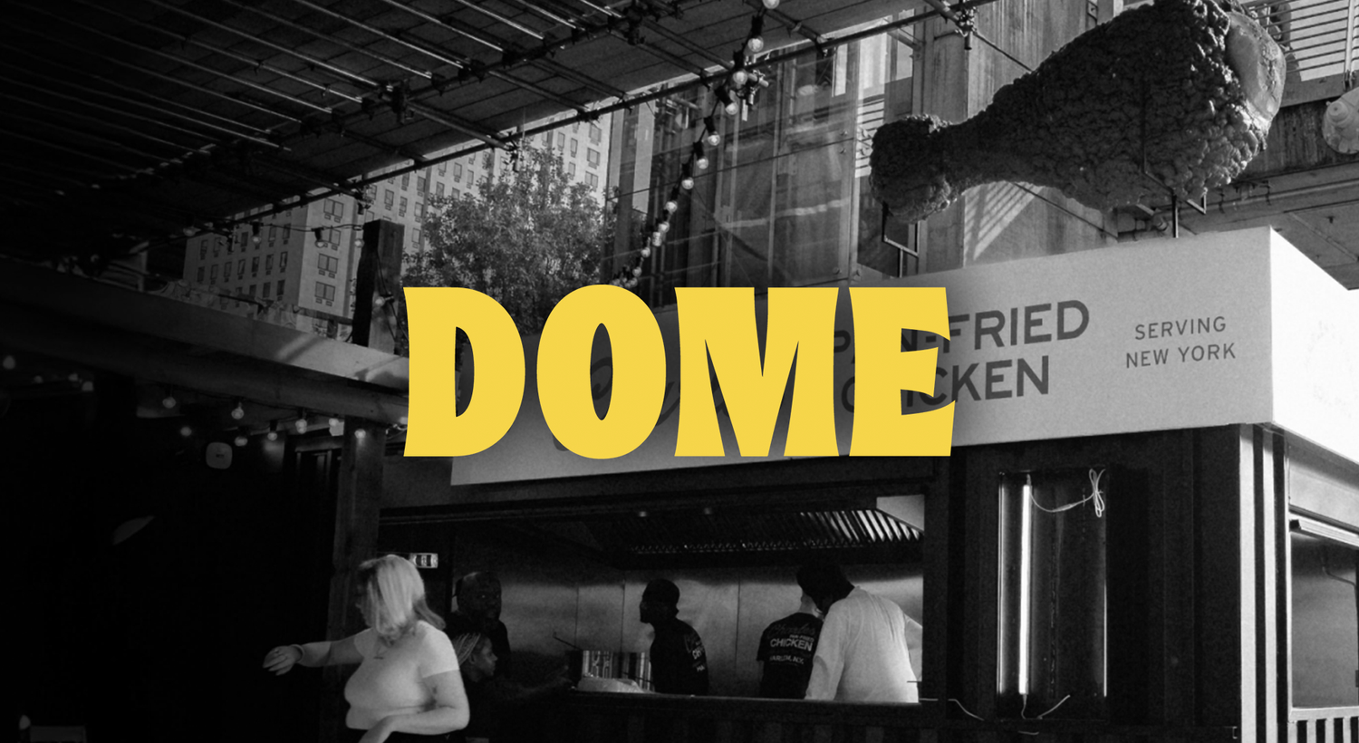 Black and white photo of a fast-food stand with a large fried chicken drumstick sculpture above and the word DOME in yellow across the image.