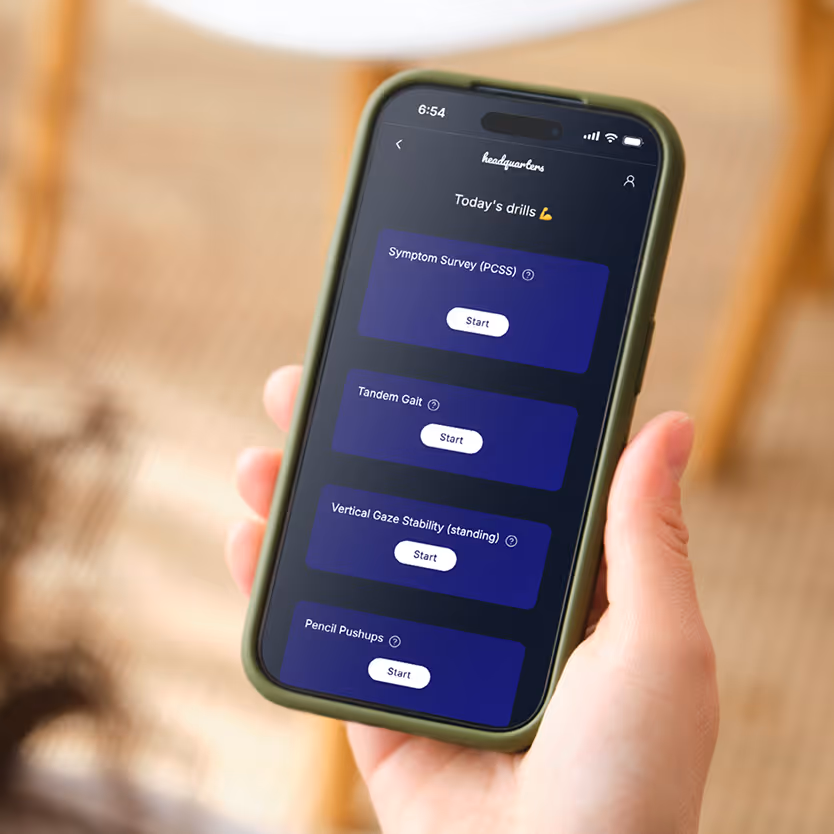 Hand holding a smartphone displaying 'Today's drills' with options for Symptom Survey, Tandem Gait, Vertical Gaze Stability, and Pencil Pushups, each with a start button.