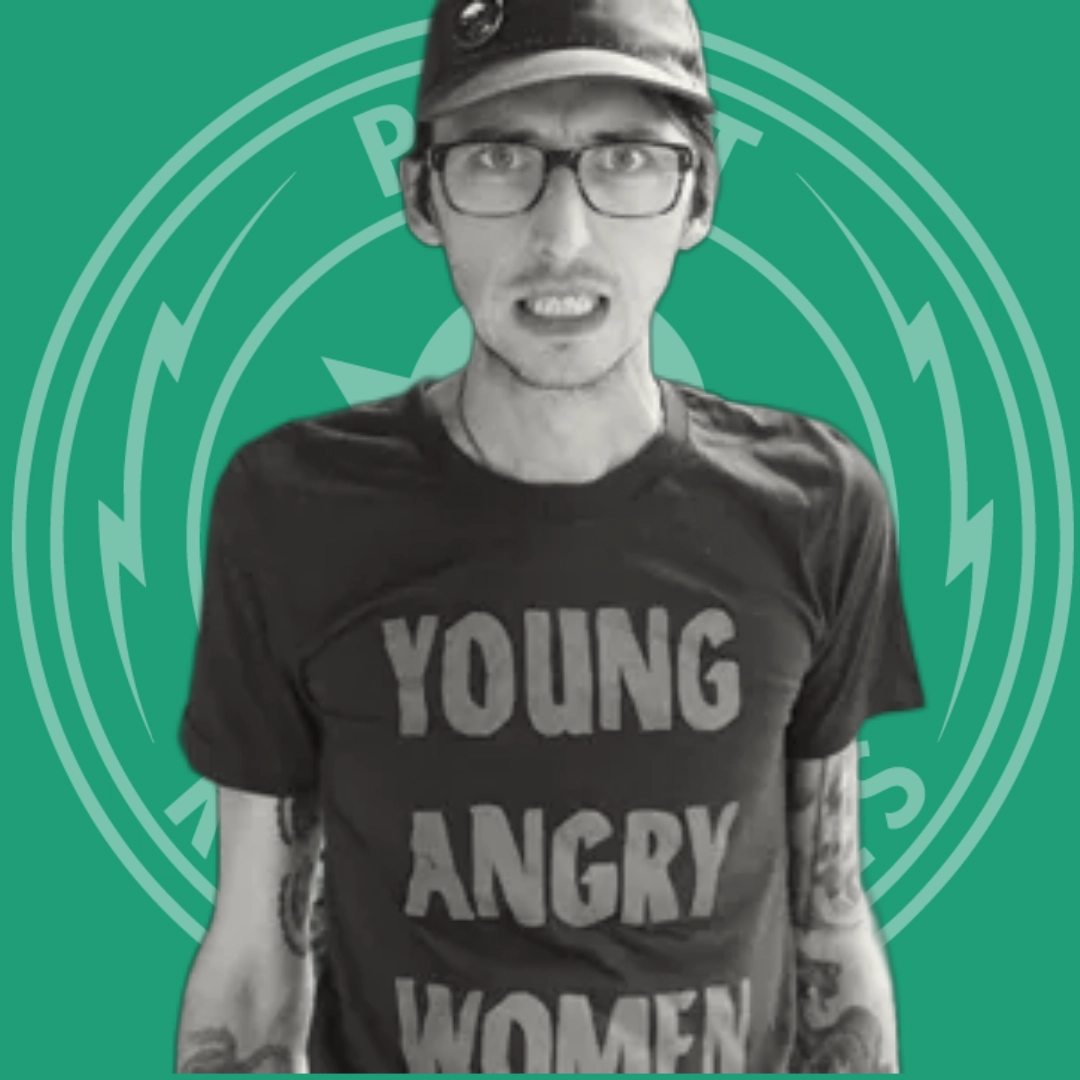 Man wearing glasses, a cap, and a black t-shirt that reads 'YOUNG ANGRY WOMEN' against a green background with a circular emblem.