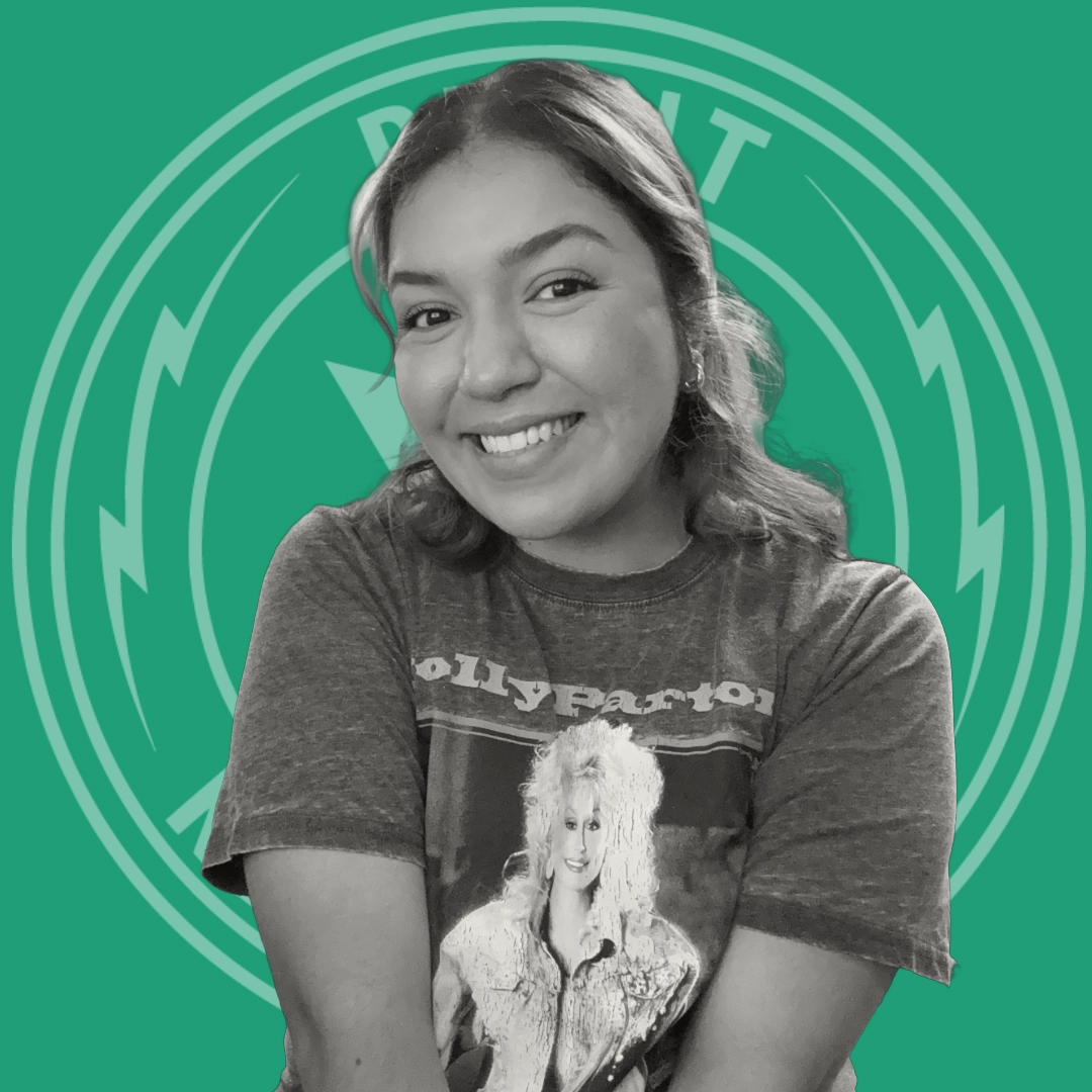 Smiling young woman with long hair wearing a vintage Dolly Parton t-shirt against a green background with circular emblem.