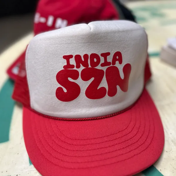White and red trucker hat with bold red text 'INDIA SZN' on the front panel.