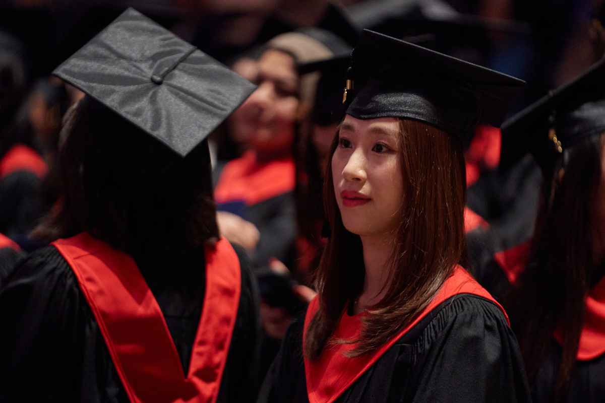 Bow Valley College graduates in red regalia standing at Jack Singer Hall