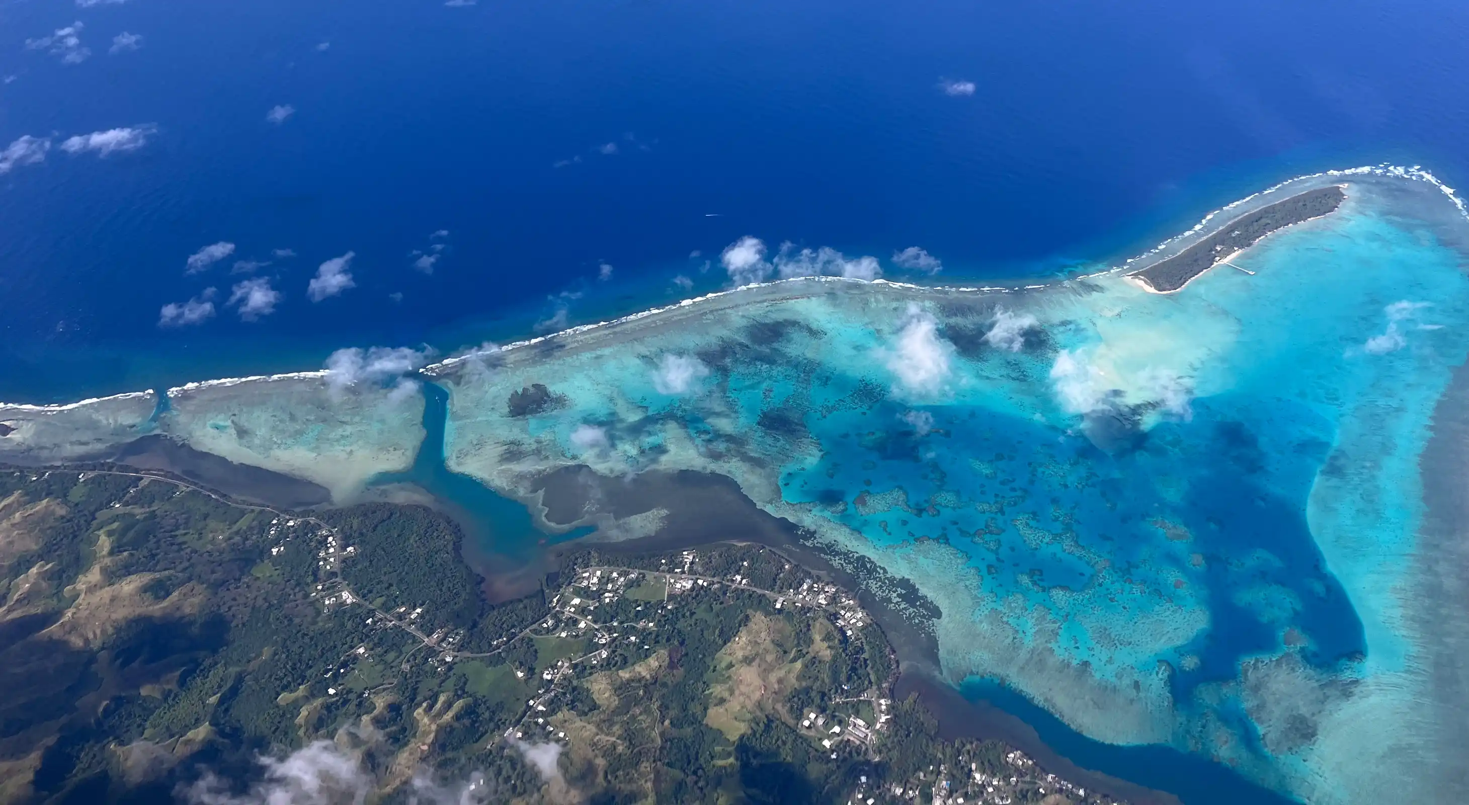 Aerial view of a large forested volcanic mountain under a clear blue sky.