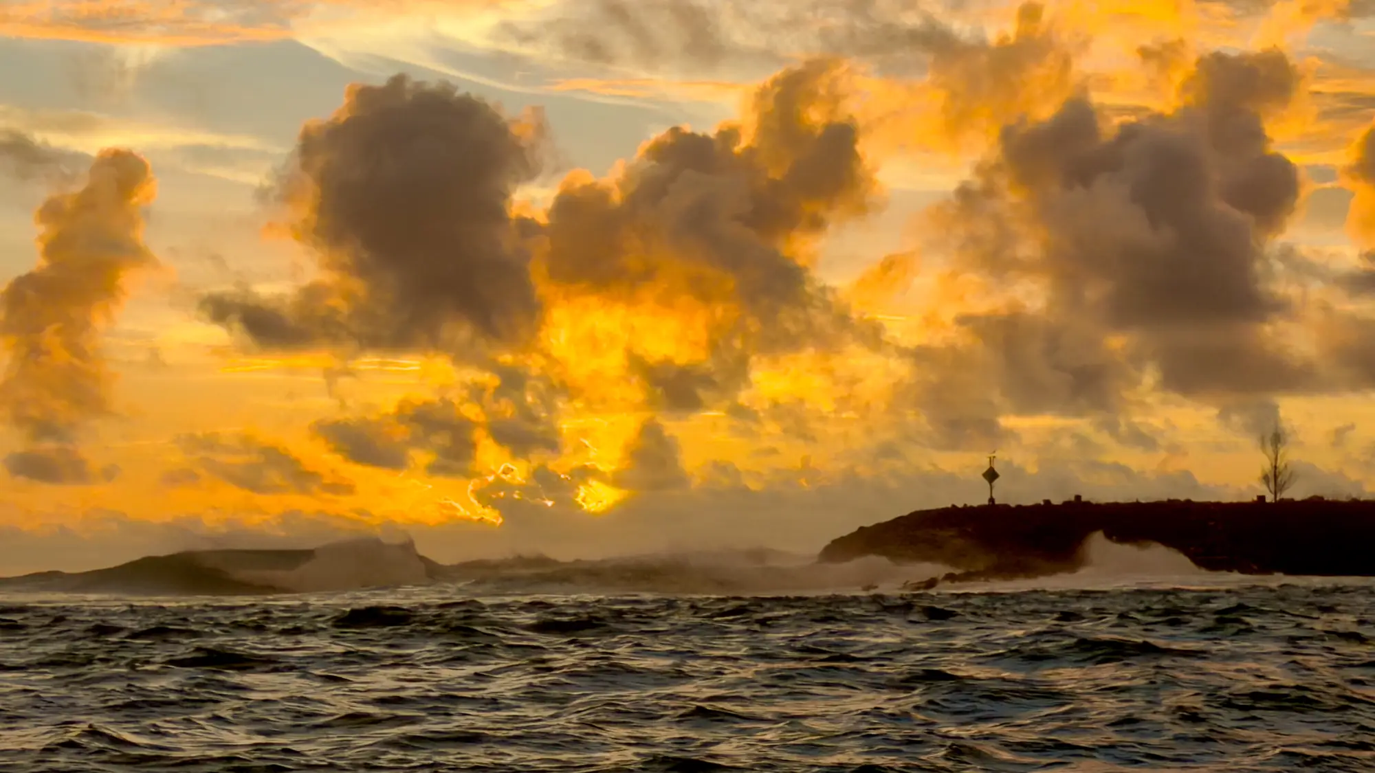 Large waves breaking against Guam’s shoreline under dramatic golden sunset clouds during field calibration work for the Global Airborne Observatory.