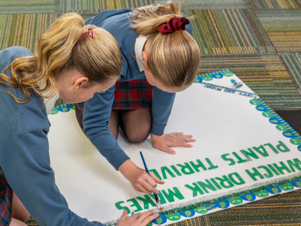 Two students using fine motor skills to paint a poster